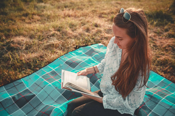 istock Young woman reads a book in nature 2122856048