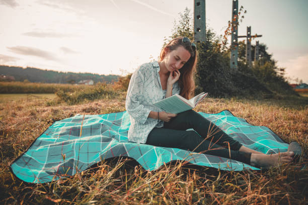 istock Young woman reads a book in nature 2122856052