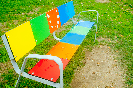 Rainbow bench painted multi colored, public park in Tui, Pontevedra, Galicia, Spain.