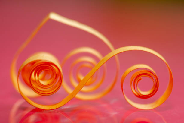 A piece of orange paper is curled into a spiral shape. The image has a warm, inviting mood, and the orange color of the paper adds a sense of energy and excitement