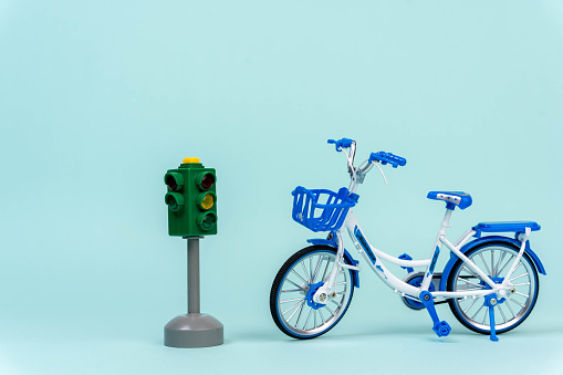 A miniature toy bike positioned next to a traffic light, symbolizing the importance of road safety for children and promoting awareness of traffic rules and regulations.