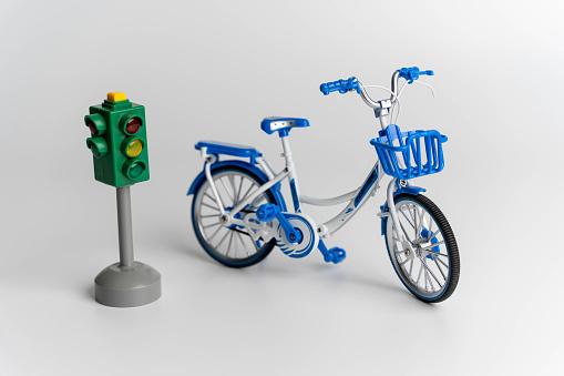 A miniature toy bike positioned next to a traffic light, symbolizing the importance of road safety for children and promoting awareness of traffic rules and regulations.