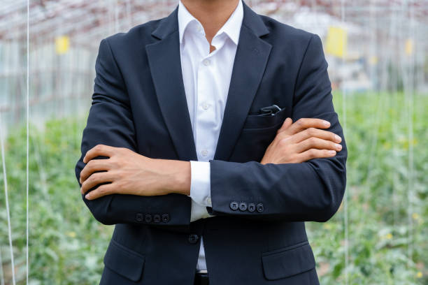 unknown entrepreneur with arms crossed looking at camera at greenhouse