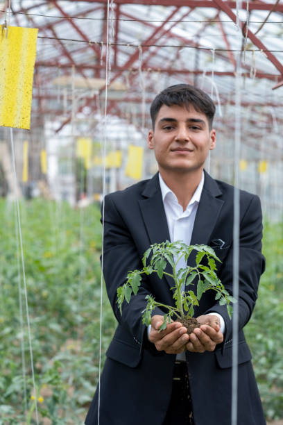 istock young man working in greenhouse holding seedlings 2122938878