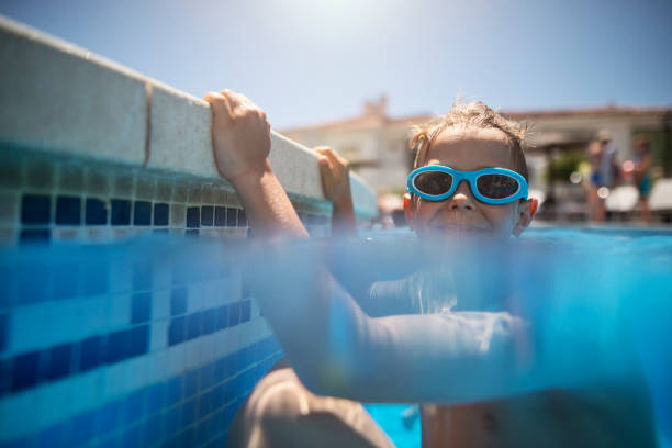 istock Happy little boy climbing pool ladder in resort pool. 2122940996