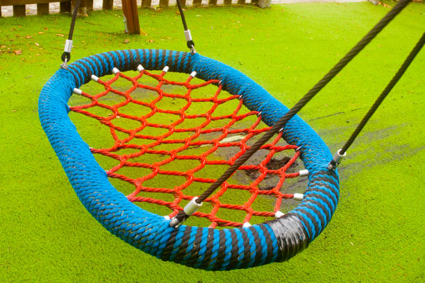 Swing rope hammock,  green soft flooring,  part of a children playground, outdoor play equipment, public park . Tui, Pontevedra province, Galicia, Spain.