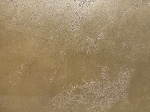 Gold or golden textured paint washed on a wall or panel, seamless texture, random texture. No people.