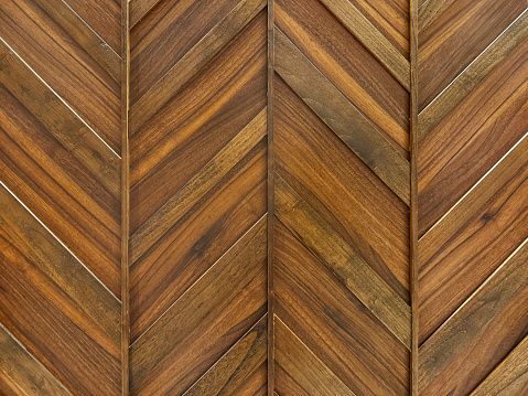 Chevron and herringbone rustic solid wooden texture and arrangements on wall panel. Solid wood varnished on wall, wood cladding.