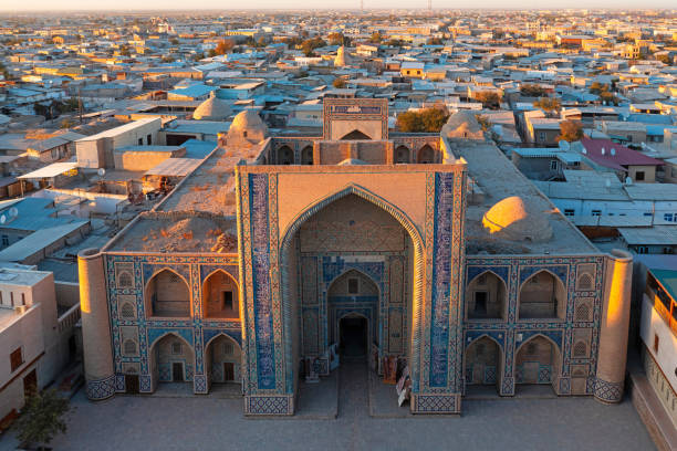 Ulugbek Madrasah Iwan Bukhara Uzbekistan Sunset Drone View Ulugbek Madrasah in Bukhara in warm Sunset Light. Ulugbek Madrasah is an architectural monument from the year 1417. It is the oldest preserved madrasah in Central Asia. Giant decorated Iwan - Entrance into the historic islamic Medrassa - School Building in the Medina of Bukhara. Drone Point of View. Ulugbek Madrasah, Bukhara, Khorezm Region, Uzbekistan, Central Asia tashkent stock pictures, royalty-free photos & images