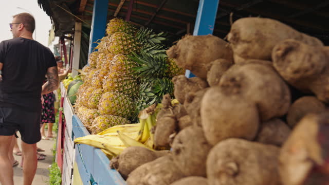 Tracking Shot of Taros and Pineapples For Sale on Market Stall