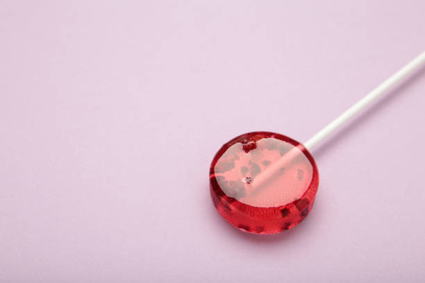 Red sweet lollipops with berries on purple background. Space for text. Top view