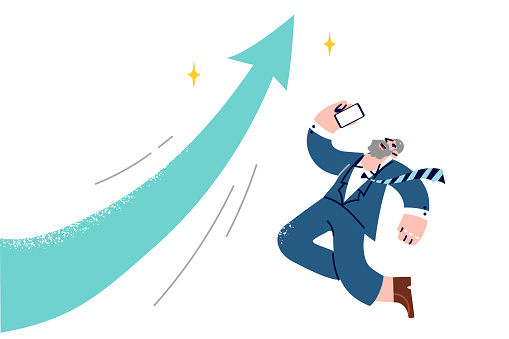 Overjoyed experienced businessman jumps to celebrate growth of company stock capitalization, near large up arrow. Elderly man in office clothes celebrate receiving SMS message on phone.