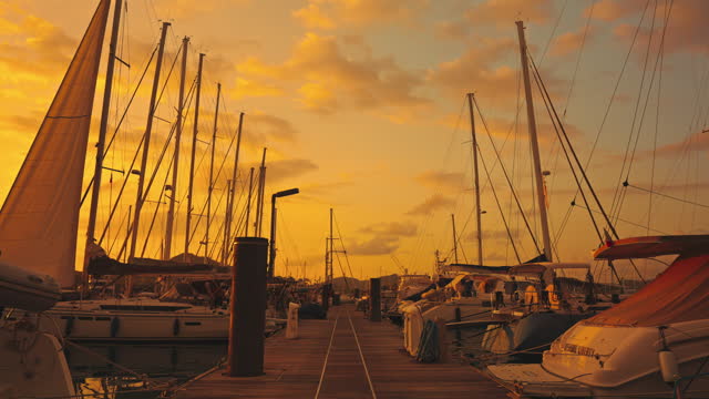 Tracking Shot of Sailboats Moored on Pier at Harbor against Cloudy Sky during Sunset