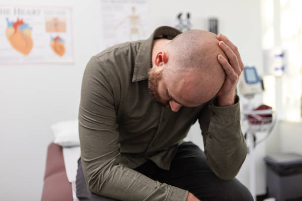 istock Worried male patient looks down while rubbing head 2123088948