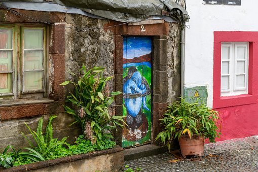 A colorfully painted door along Rua de Santa Maria, a narrow alley of shops and sidewalk cafes in the Art of Open Doors artistic district of the old town of Funchal, Portugal, on the Canary Island of Madeira in the Atlantic Ocean.