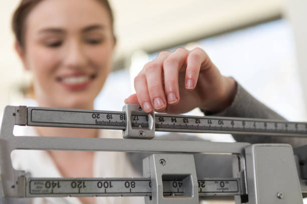 istock Focus on smiling woman's hands adjusting weights on beam scale 2123094175