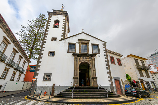 The whitewashed facade and bell tower of the 18th century St. Peter's Catholic Church, or Igreja de São Pedro, in the historic old town district of Funchal, Portugal, on the Canary Island of Madeira in the Atlantic Ocean off the coast of Africa.
