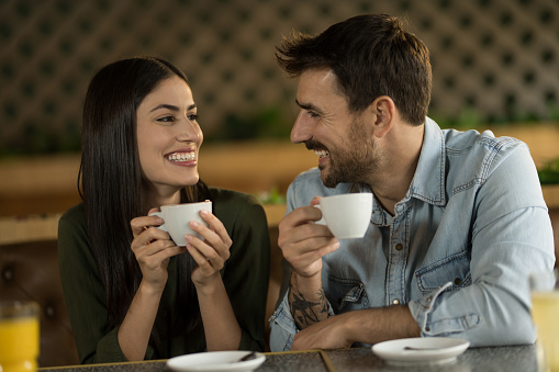 Happy young couple enjoying coffee at a cafe and talking while on a date.