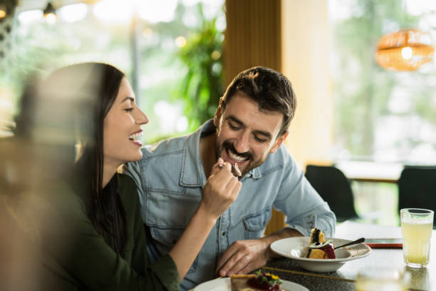 istock Happy young couple feeding each other cakes in a restaurant. 2123106378