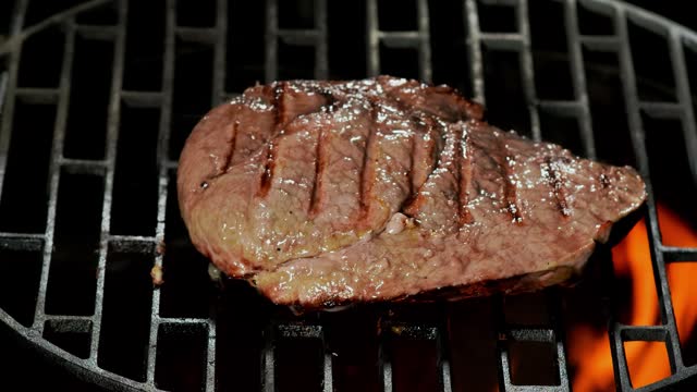 Beef steak lies on the grill on an open fire
