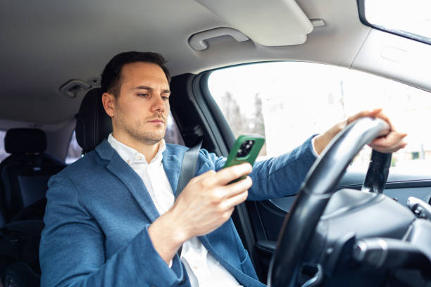 istock Irresponsible Caucasian businessman, using mobile phone, while driving the car 2123155215