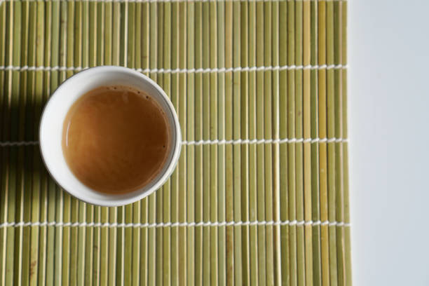 In the image, there are a pair of chopsticks resting on a bamboo sushi rolling mat, next to a small bowl filled with soy sauce. The natural textures of the bamboo and the traditional utensils evoke the essence of Japanese cuisine and the art of sushi making.