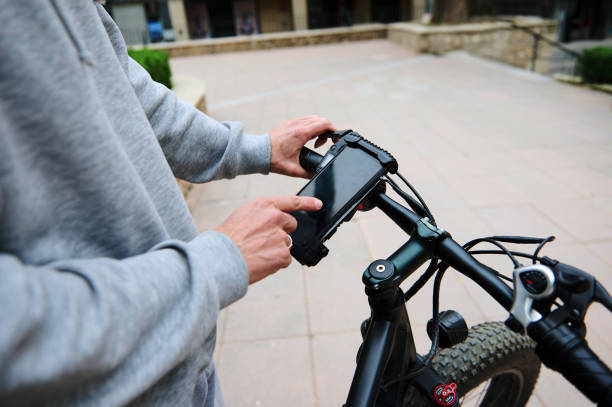 istock Close-up cyclist checks mobile app on smartphone Mockup digital touch screen, setting up a route on internet online map 2123220130