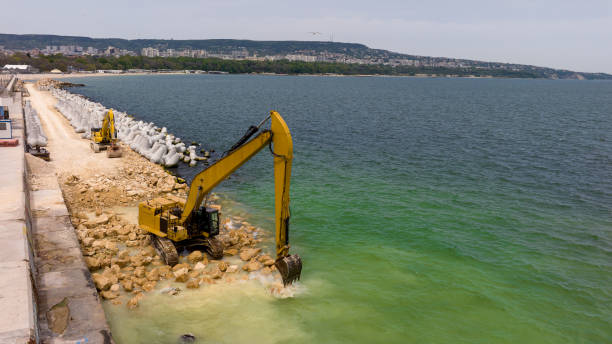 istock Aerial view of waterfront construction site with excavator. Excavator working on a breakwater construction 2123222218