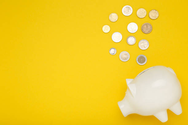 istock Piggybank with coins on yellow background 2123239975