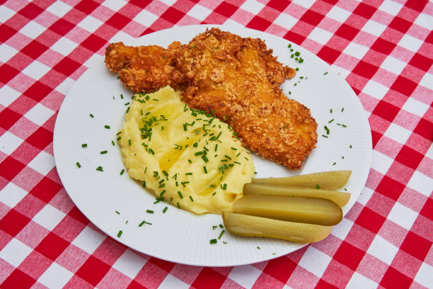 Chicken schnitzel with mashed potatoes and pickled cucumbers.