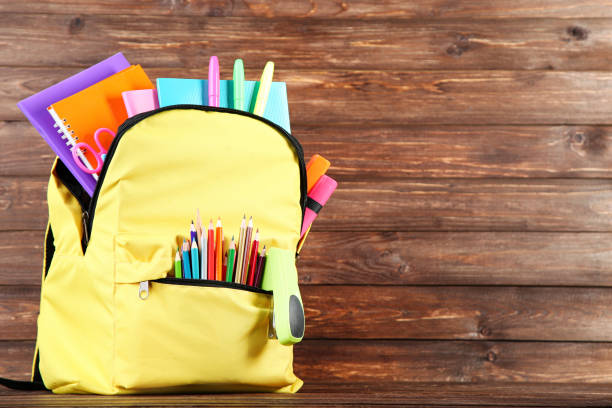 istock Backpack with school supplies on brown wooden background 2123260724