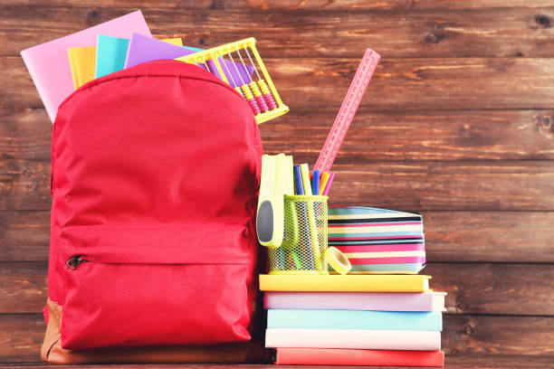 istock Backpack with school supplies on brown wooden background 2123264344