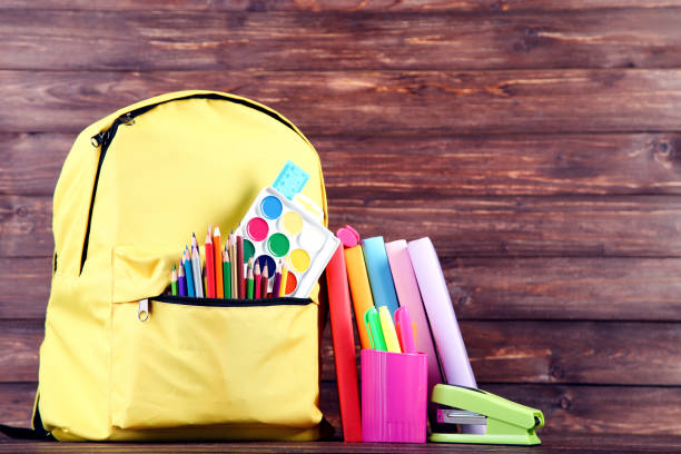 istock Backpack with school supplies on brown wooden background 2123284014