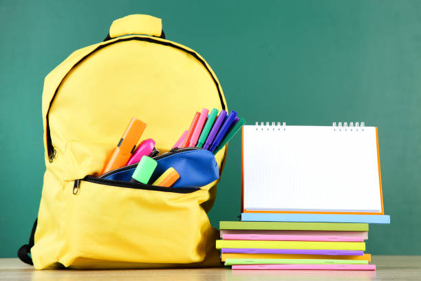 istock Backpack with school supplies and blank notepad on chalkboard background 2123290758