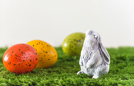 Easter bunny and multicolored easter eggs on a green grass; Copy space