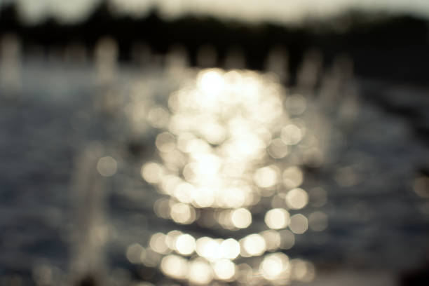 Fountain is a blurred background of water. The glare in the sun is in motion. Abstract natural background. The concept of summer coolness, cooling in the heat. Shallow depth of field, beautiful bokeh