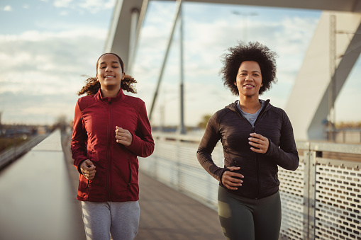 Fitness, sport, family and lifestyle concept - smiling black family running outdoors on the bridge. Living healthy lifestyle.