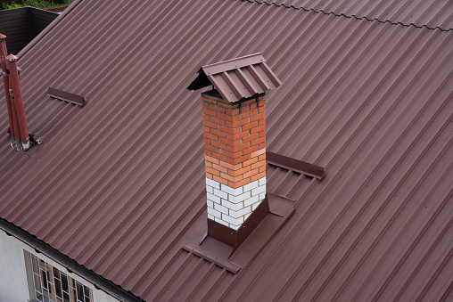 Brick chimney on the metal roof of the house
