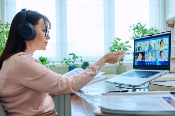 istock Woman teacher in headphones teaching online, high school students on computer screen 2123404978