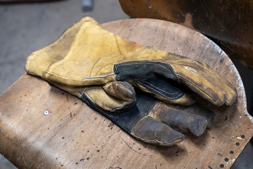 Dirty, yellowwork gloves thrown on an old chair in a workshop