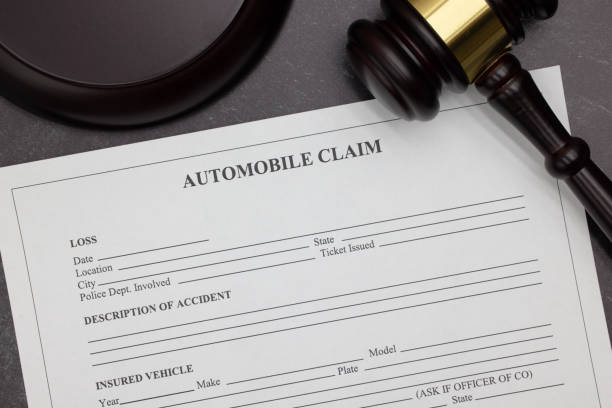Automobile Insurance Claim form with gavel and block on slate desktop