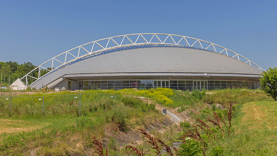 Indjija, Serbia - July 03, 2023: Steel Arch Metal Dome Structure Sports Hall Complex at Sunny Summer Day.