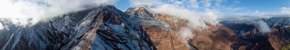 View of the slope rocky mountain above fog and clouds. Creamy