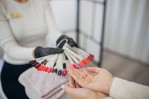 Close-up view of a manicurist presenting a variety of nail polish samples to a client