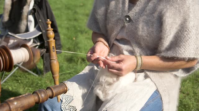 Woman Spins Sheep's Wool with a Spinning Wheel.