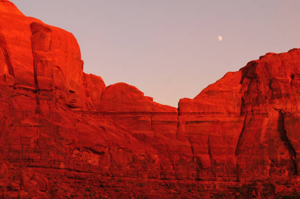 la luna e le scogliere di arenaria illuminate dal tramonto della monument valley - the western wall foto e immagini stock