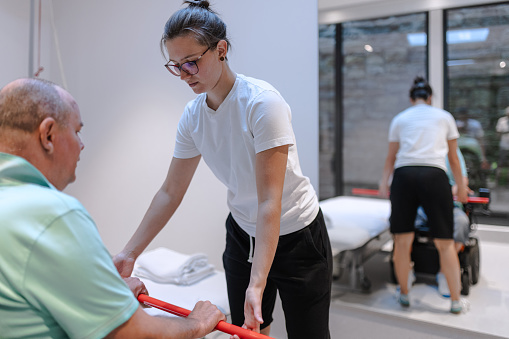 A physiotherapist does rehabilitation exercises with a disabled person on the therapy table.