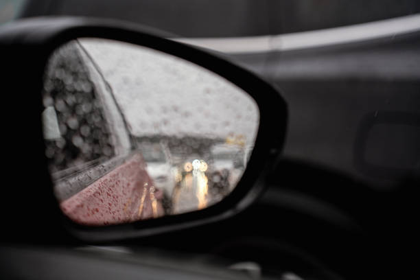 Raindrops reflected on the car glass and rearview mirror on a rainy day