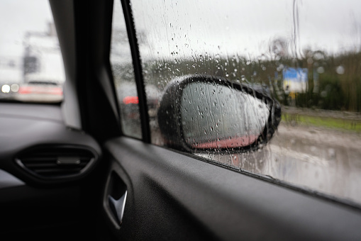 Raindrops reflected on the car glass and rearview mirror on a rainy day