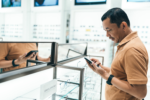 Man selecting eyeglasses in optical store